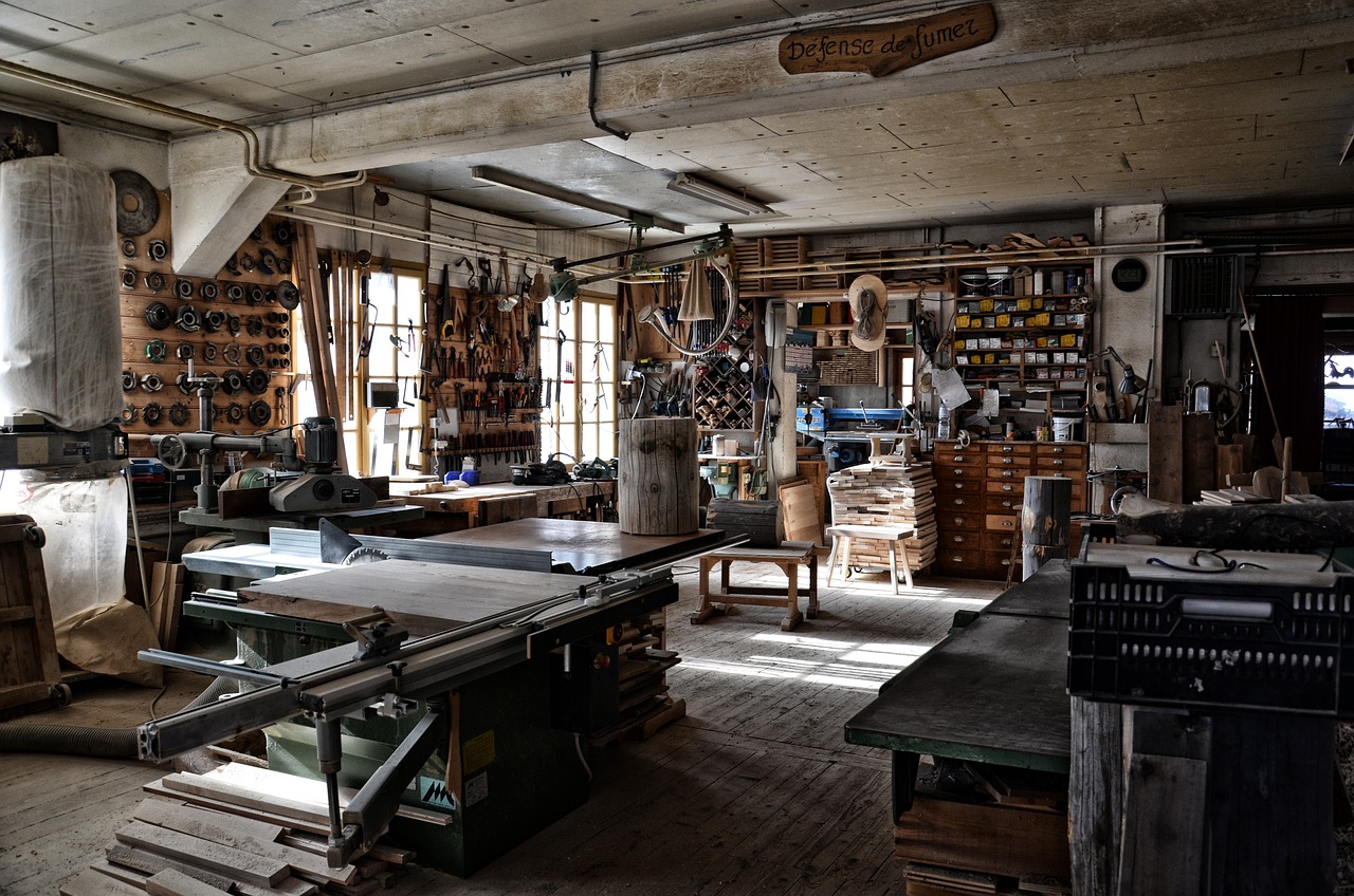 Atelier de menuiserie désert, outils rangés le long du mur, lumière du matin par la fenêtre